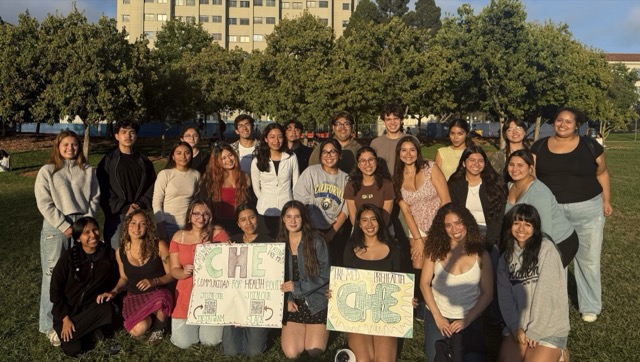CHE members outdoors holding signs for Comunidad for Health Equity
